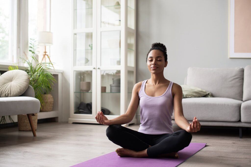 African American Woman meditating mindfulness and practicing yoga at home.