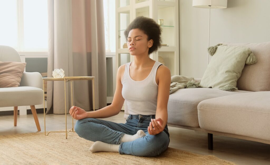 Black woman meditating while sitting at home.